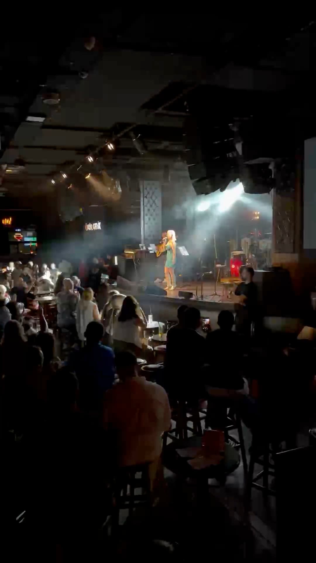 Konser gecesi "Hovarda" — ışıklar altındaki sahne ve ayakta eşlik eden salon